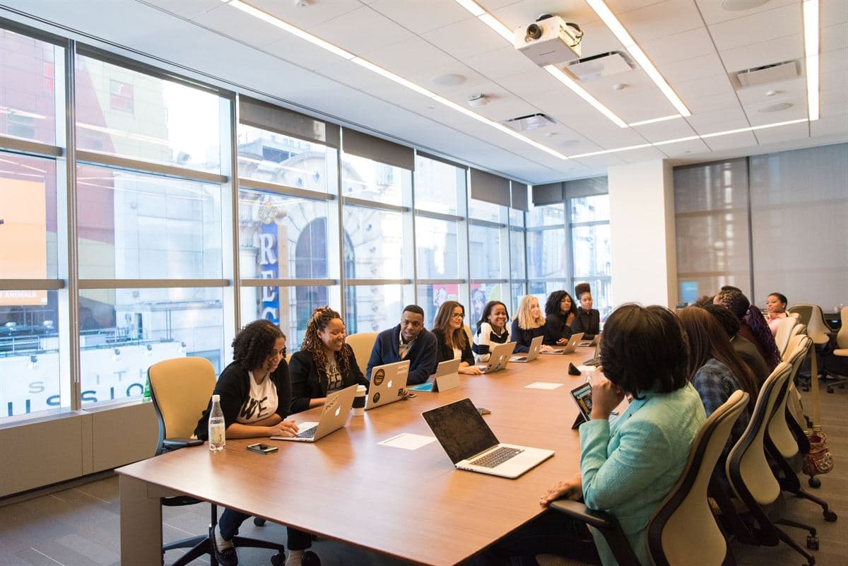 Femmes et hommes réunis autour de la table d'une salle de conseil lumineuse